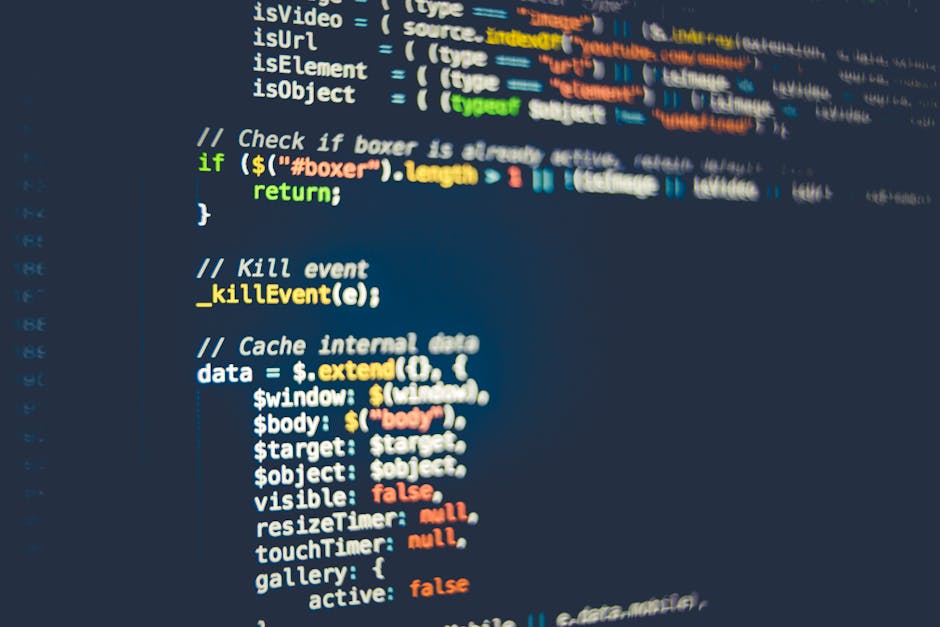 Close-up image of a computer screen displaying lines of code with syntax highlighting in various colors, including green, yellow, orange, and white on a dark background. The code appears to be HTML, f